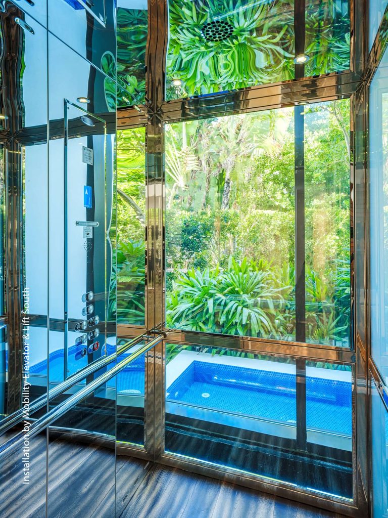 Savaria Orion Commercial Glass Elevator With Views of Greenery and Swimming Pool.