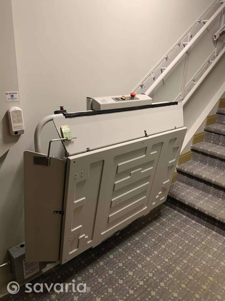 Savaria Delta folded incline platform lift on a staircase, featuring a control panel with buttons.