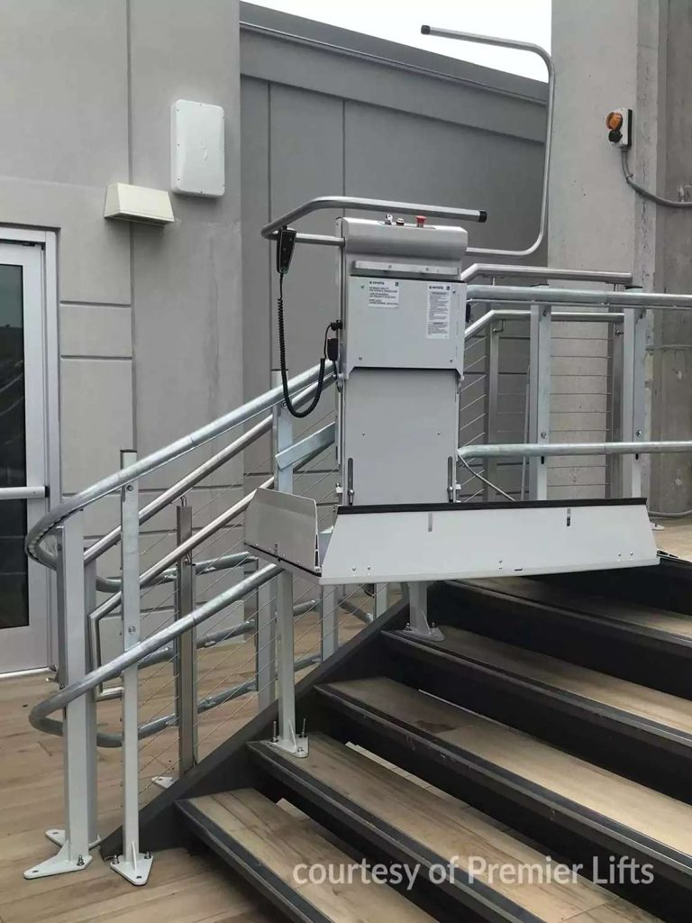 Savaria Omega Inclined Wheelchair lift top landing on a staircase with metal rails and wooden steps.