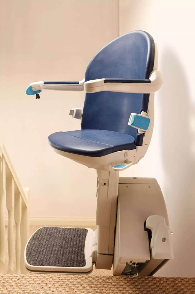 Handicare 1000 Stairlift with a blue seat and backrest installed on a staircase with a beige carpet.