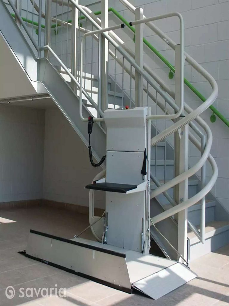 Savaria Omega unfolded Inclined Platform lift system installed beside a staircase with green-accented handrails.