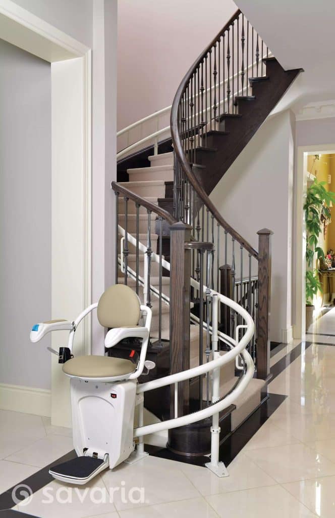 Savaria Stairfriend 23 on a spiral staircase with dark wooden steps beige seat and white rail.