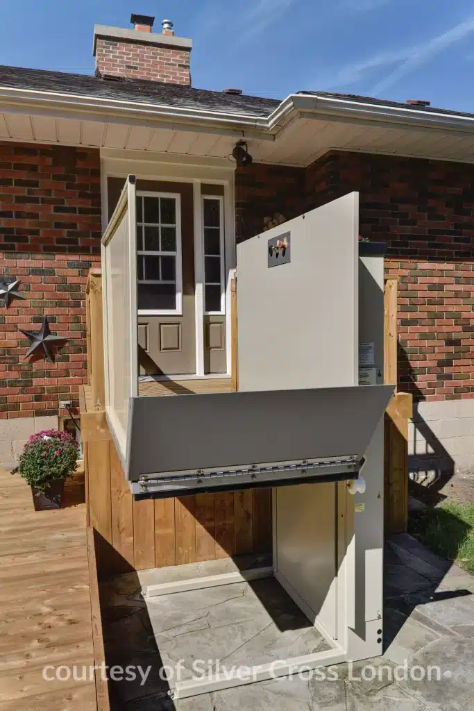 Savaria Multi lift Outdoor Residential Platform lift next to a brick house with a wooden deck.