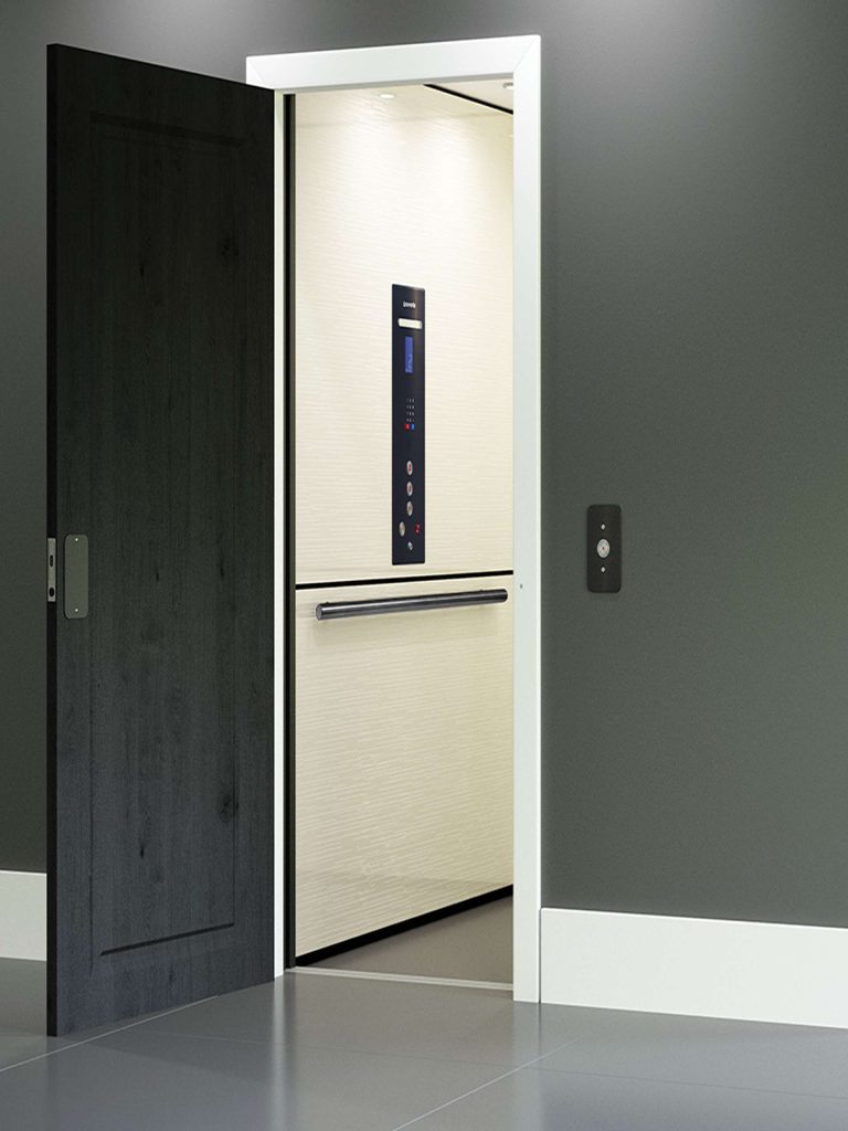 Interior of Savaria Zenith Home Elevator seen through an open doorway featuring light-colored walls a control panel and a black sliding door.