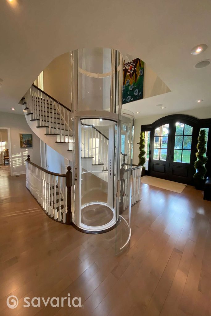 Interior of Savaria Vuelift Mini cylindrical glass elevator, spiral staircase, and open foyer.