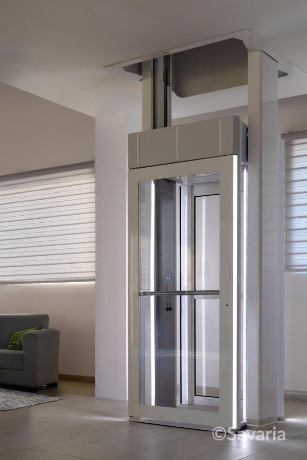 Compact glass Savaria Luma home elevator with white framing in a modern room.