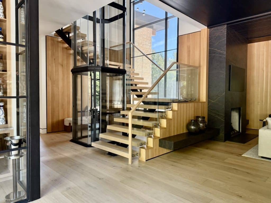 Interior view of a modern Savaria Vuelift glass elevator, wooden staircase